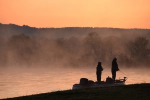 Father and son fishing at sunrise at Cane Creek, boasting boat slip rental on Kentucky Lake.